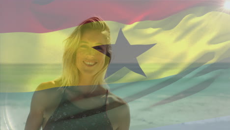 Animación-De-La-Bandera-Ondeante-De-Ghana-Sobre-Una-Mujer-Caucásica-Sonriente-Parada-Contra-El-Mar-En-La-Playa