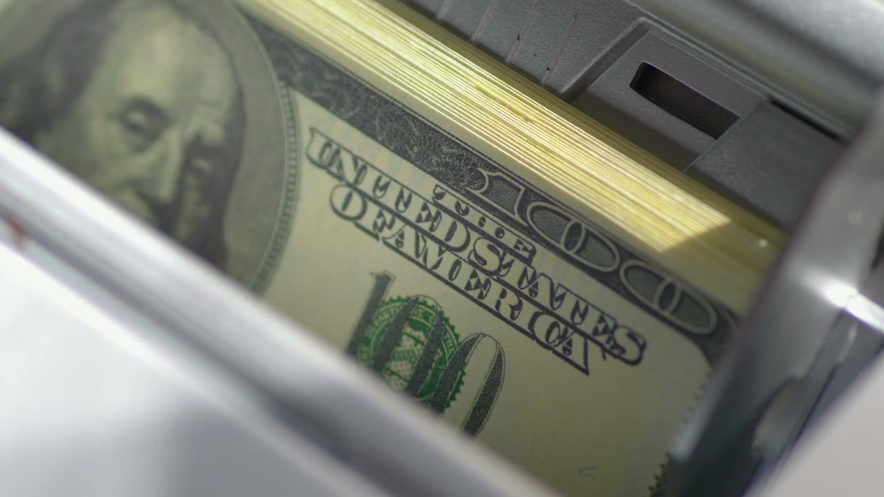 Máquina contadora automática calculando una gran cantidad de billetes de dólar en cámara lenta 4K a 60fps