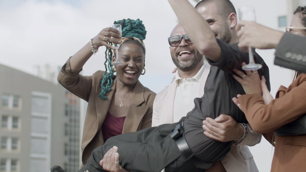 compañeros de trabajo sosteniendo al líder del equipo en manos de la fiesta de negocios