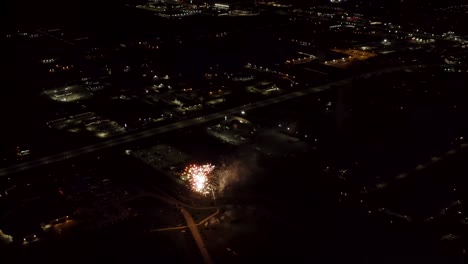 toma aérea de fuegos artificiales con luces de la ciudad en el fondo