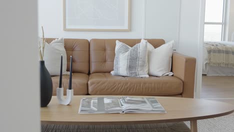 straight angle dolly shot of the living area in a high ceiling penthouse condominium unit showing the details of the leather sofa and coffee table during a sunny day