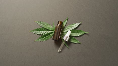 Video-of-marijuana-leaves-and-bottle-of-cbd-extract-on-grey-background