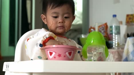 cute asian baby licking finger after eating rice vermicelli at home