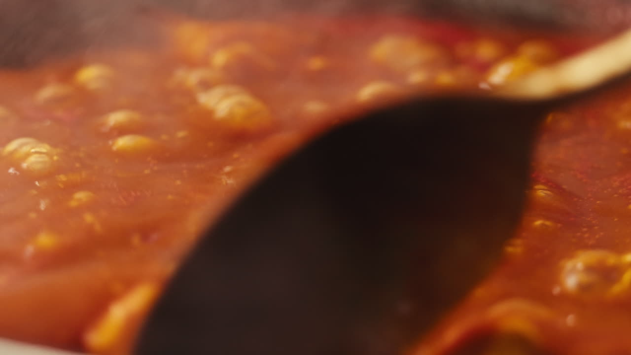 Chicken in tomato sauce is boiling on a frying pan with spices. Cooking tomato sauce curry with chicken fillet. Traditional Italian Mexican Asian dish. High quality studio shot for cafe, restaurant close up.