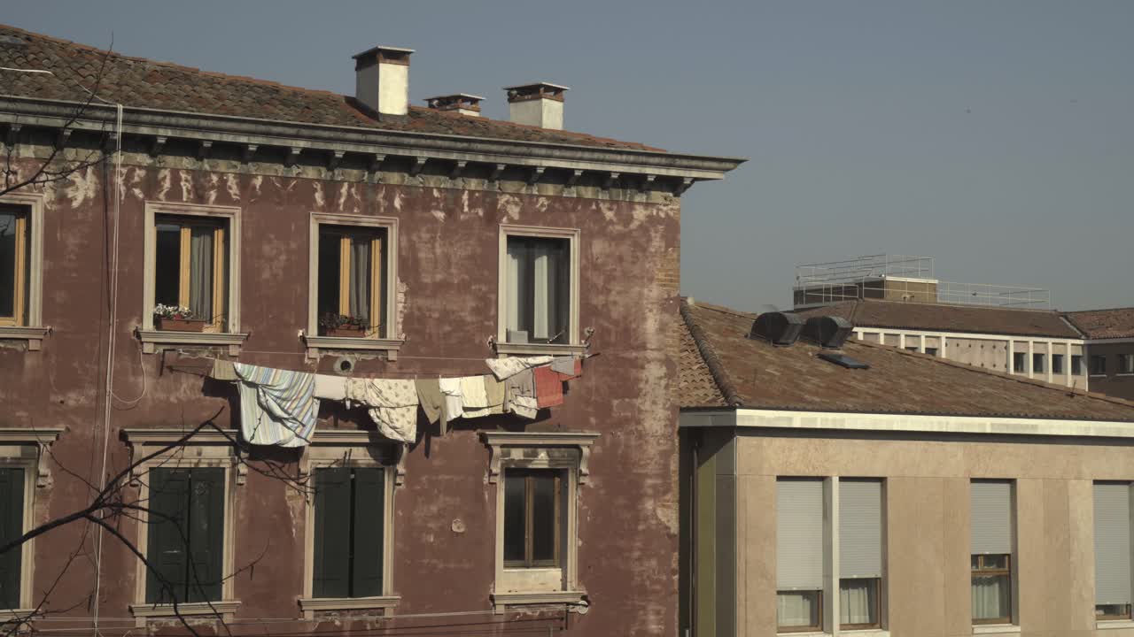 Vestiti stesi ad asciugare su un filo fuori da un edificio tradizionale e invecchiato a Venezia, che mostra la vita quotidiana