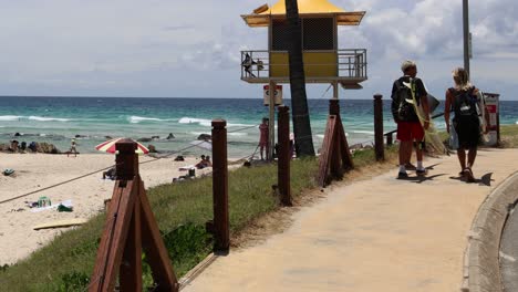 two surfers walking along a beach path