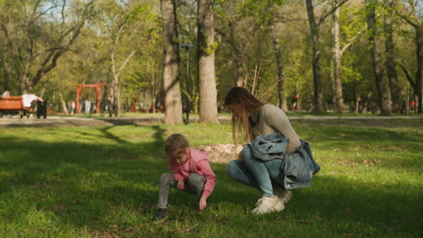 mädchen und mutter suchen nach käfern im rasen in spring park