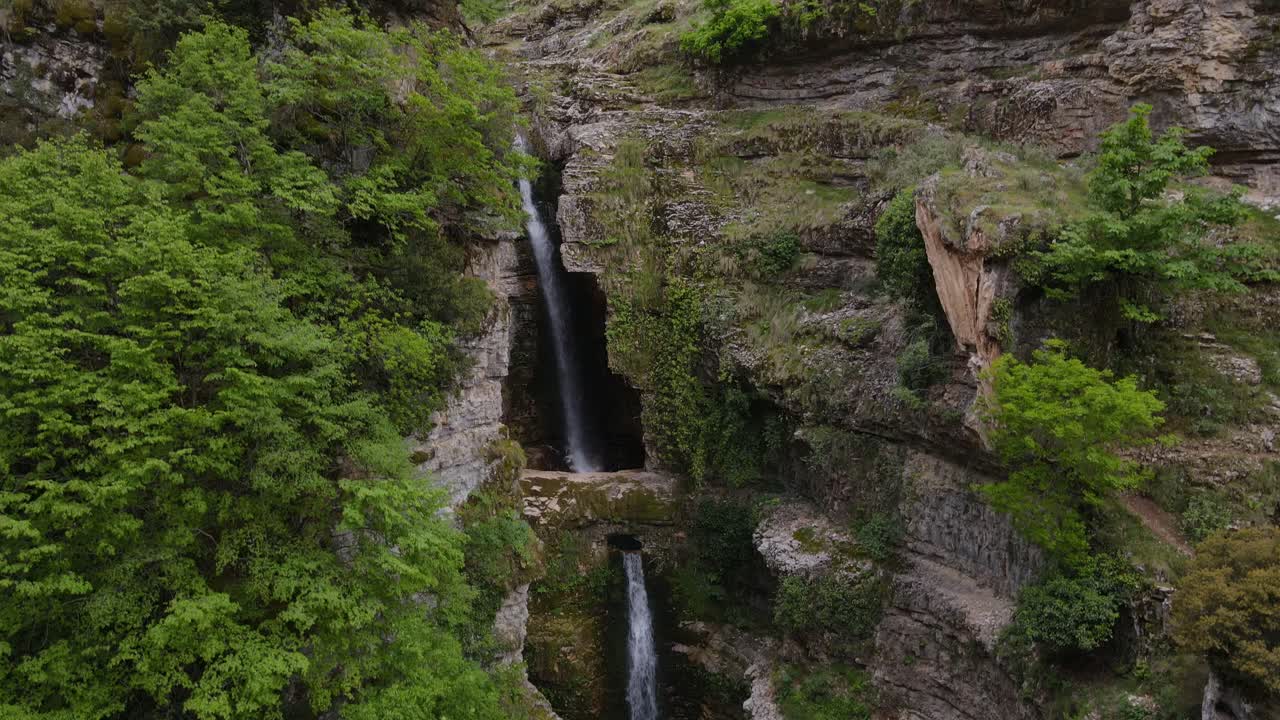 Upward aerial view of Blue Voyage Albania - Ujvara e Peshtur&euml;s, Tepelena, with water cascading down the waterfall