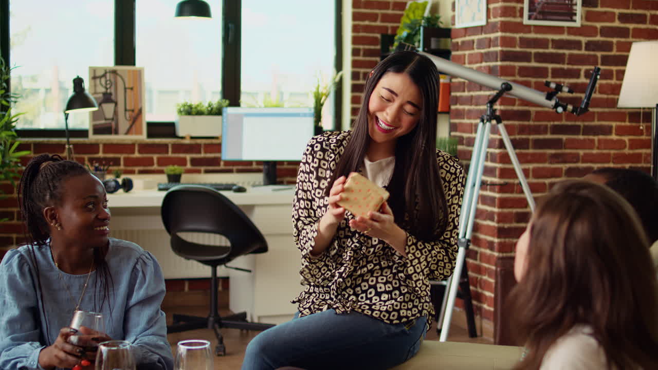 Multiethnic friends throwing surprise birthday party for woman, giving her thoughtful gift