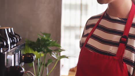 Waitress-wiping-espresso-machine-with-napkin-in-cafÃ©