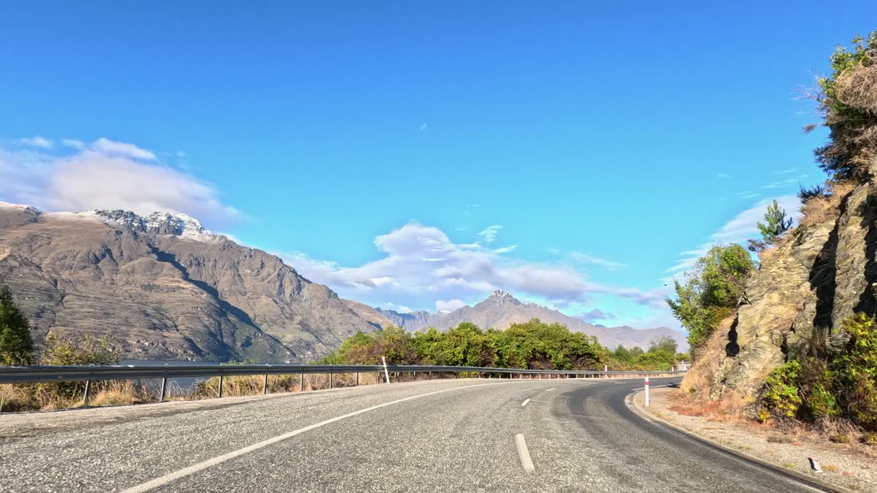 Car travels winding mountain road, bright daylight, scenic landscape, dynamic forward camera movement, clear sky