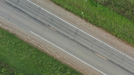 diagonal aerial view of rural two-lane road, drone flying right to left