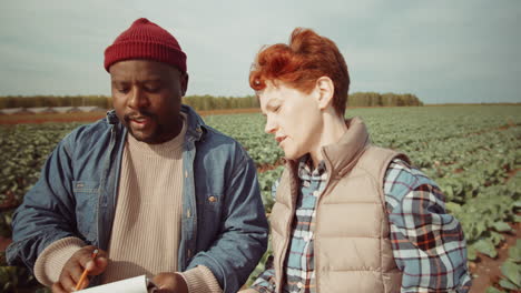 diverse male and female farmers working together on field