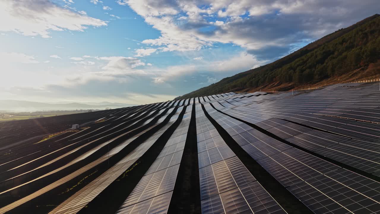 Solpaneler på en bjergside med blå himmel og skyer i baggrunden