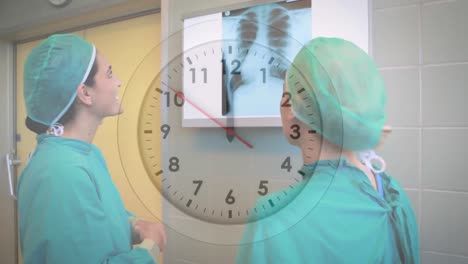 animation of ticking clock over two diverse female surgeons discussing over x-ray report at hospital