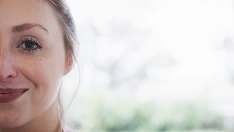 Half-portrait-of-caucasian-young-woman-smiling-against-window-with-copy-space