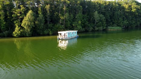 house boat floating on a lake next to a forest on a very sunny day in brandenburg, germany