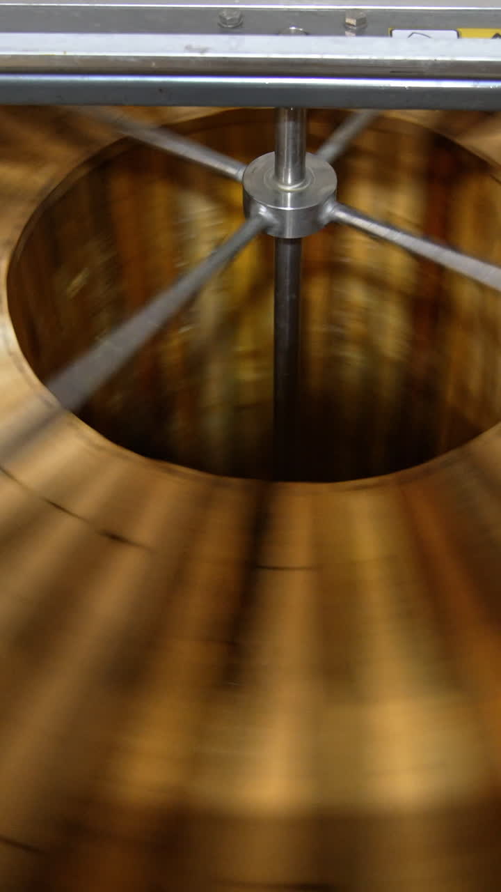 Wooden frames with organic honey being rotated quickly in the centrifuge machine. Apiarist gathering honey harvest on his farm. Vertical video