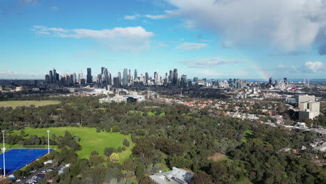 melbourne australia cbd from the air view from parkville on nice sunny day and bit of cloud rainbow in the distance looking at melbourne sporting complex royal park green parks and lot's of trees