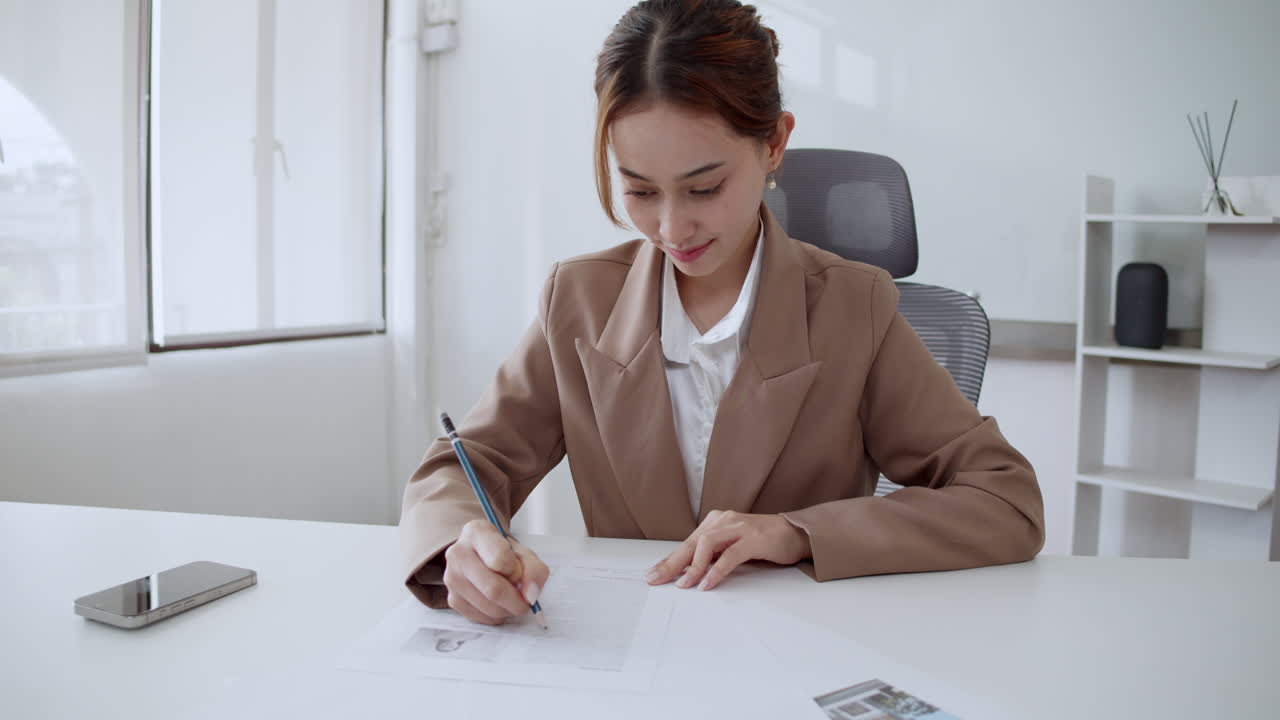 A businesswoman diligently signs important documents in a sleek office environment.