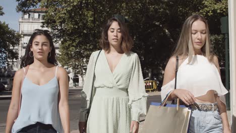 young lady walking along street with shopping bags, smiling