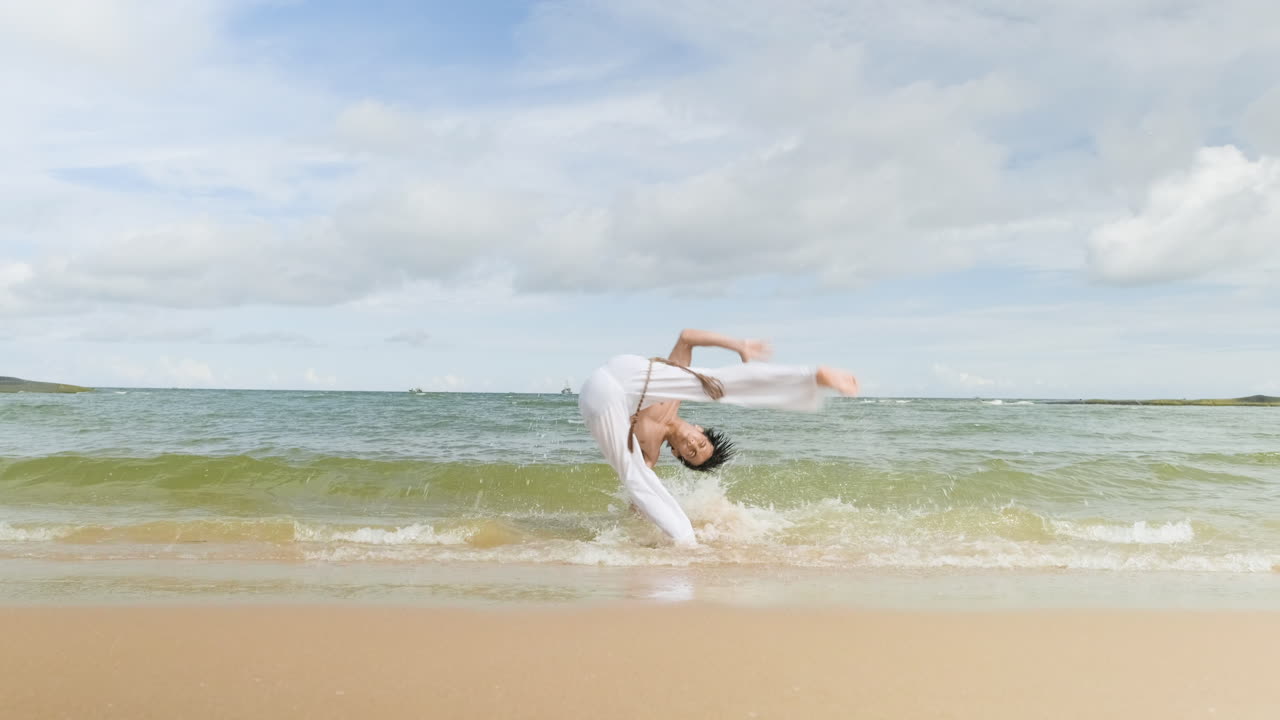 un tipo bailando capoeira en la playa.