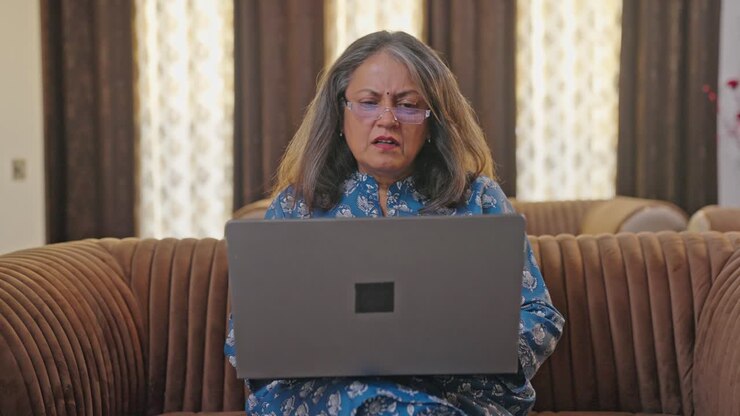mujer india de edad tratando de usar una computadora portátil por primera vez