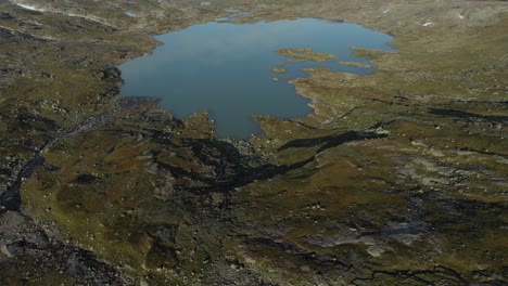 hardangervidda glacial lake with glacier in background, norway, aerial reveal