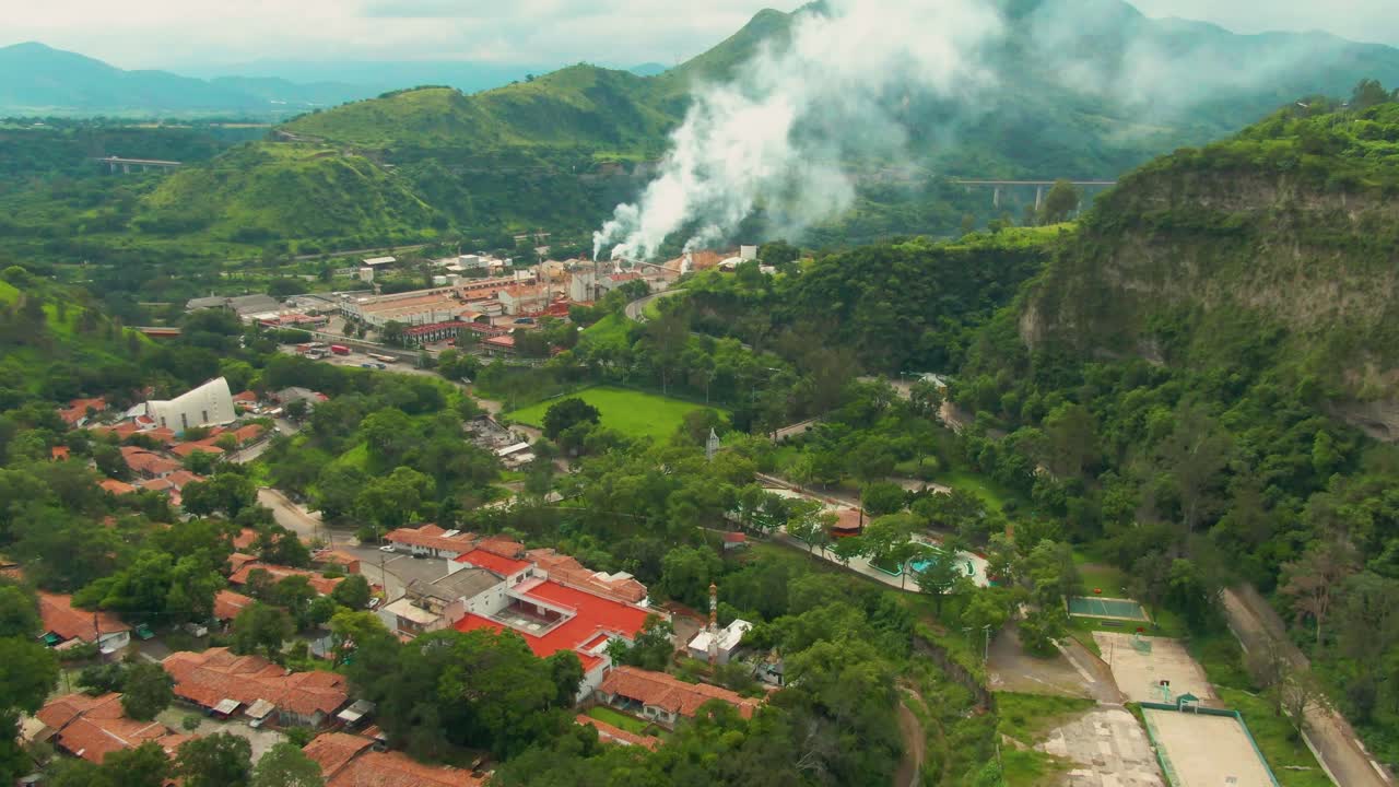 Aerial footage of Atenquique paper mill in Jalisco, with nearby town and smoke in distance