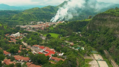 aerial footage of atenquique paper mill in jalisco, with nearby town and smoke in distance