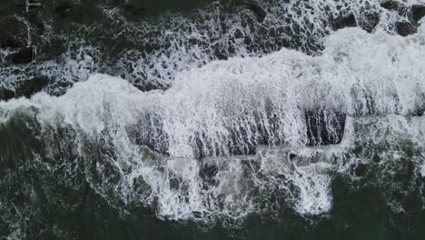 overhead view of swell crashing against the rocks. - aerial shot