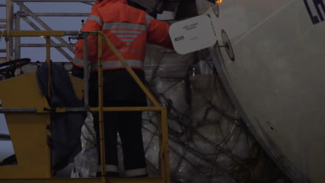 un trabajador del aeropuerto en el ascensor observando la entrega de la carga