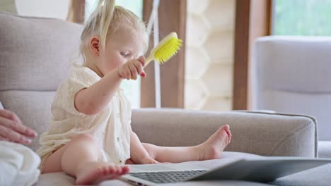 baby girl playing with brush on laptop