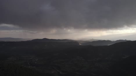 this drone video captures a stunning frontal descriptive shot over the hecho valley in the aragonese pyrenees, spain, at sunset with dramatic cloudy skies and distant storms enhancing the scenery.