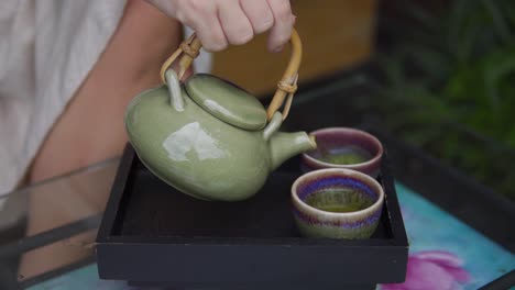 Eine-Nahaufnahme-Der-Hände-Einer-Frau,-Die-Heiße-Getränke-Aus-Einem-Wasserkocher-In-Die-Tasse-Gießt