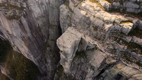 hiker and tourist figures on top of preikestolen, norway. top down shot of rock platform at lysefjord.