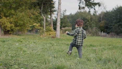 an active farm boy walks in the yard, eats a big apple on the go