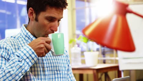 ejecutivo de negocios masculino tomando café mientras usa una tableta digital