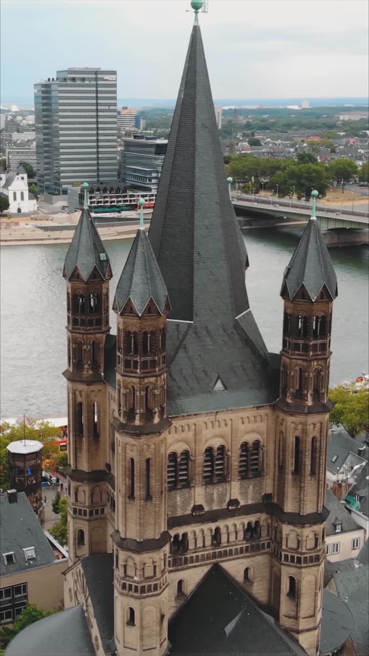 Aerial view of the Great Saint Martin Church, a Romanesque Catholic church in Cologne, Germany, with the Rhine river in the background. Vertical Video, orbit motion