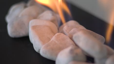 Close-up-slow-motion-tracking-shot-of-pebbles-with-gas-fire-in-between-them