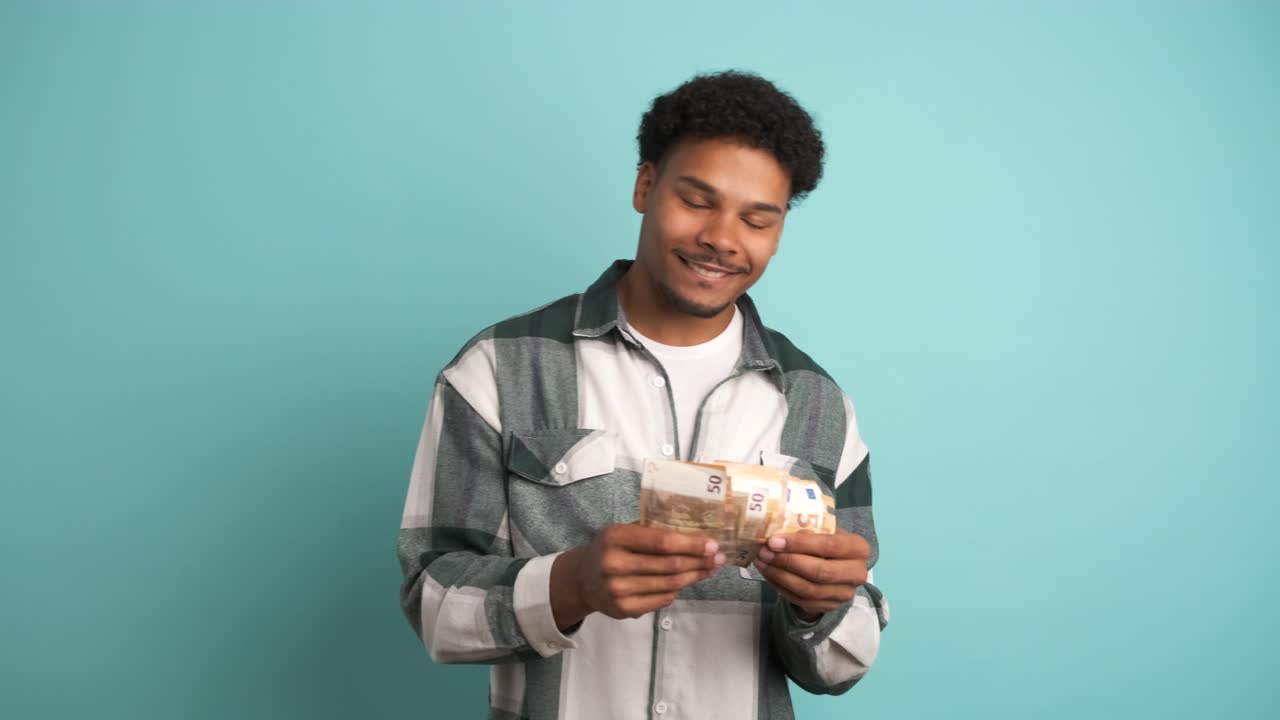 Cheerful rich man counting Euro banknotes in blue studio