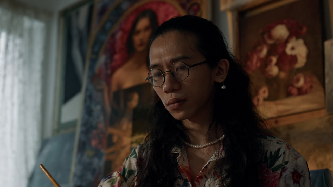 Painter with glasses working in a studio, focused and inspired