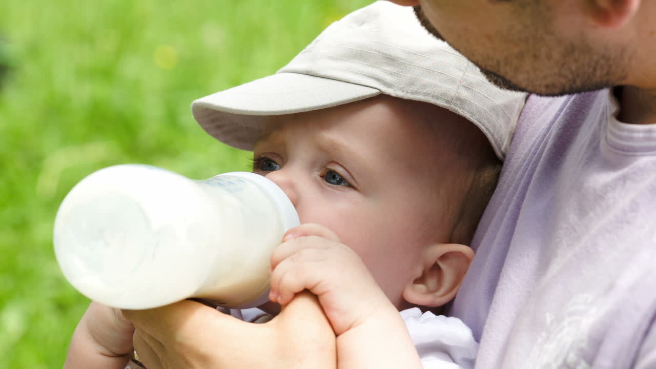 Papà che nutre il suo bambino con il biberon all'aperto