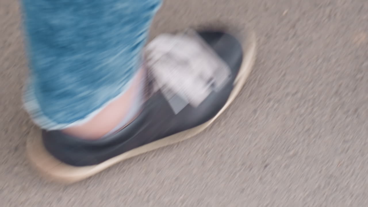 Caucasian Woman Sneaker Closeup Beside Wheelchair Wheel On Pavement Showing Denim Cuff And Tire Detail, Asphalt Texture And Partial Wheel Hint Of Mobility And Independence, Inclusive Disability