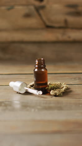 video vertical de brotes de marihuana y botella de extracto de cbd en fondo de madera