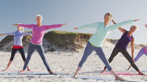 athletic women performing yoga in the beach