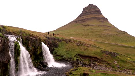 two persons walk near a beautiful waterfall