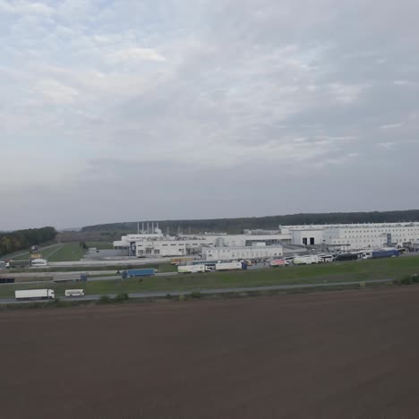 industry among fields. modern industrial zone in nature. large factory with parking places with cars and trucks. trucks moving on the road. view from the air.