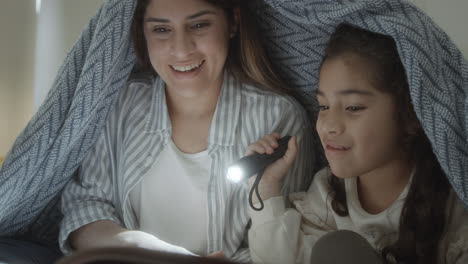 loving mother reading fairytale to little daughter at night