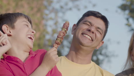 close-up of happy preteen boy giving shashlik to his father